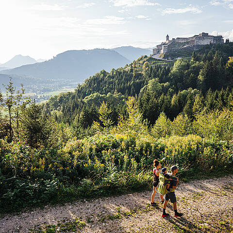 Eine Familie – Mama, Papa und ihr Kind – spaziert entspannt auf der Burgherrenrunde rund um die Burg Landskron.