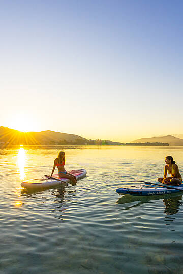 Zwei Damen bei Sonnenuntergang am Woerthersee mit Boot und Paddel