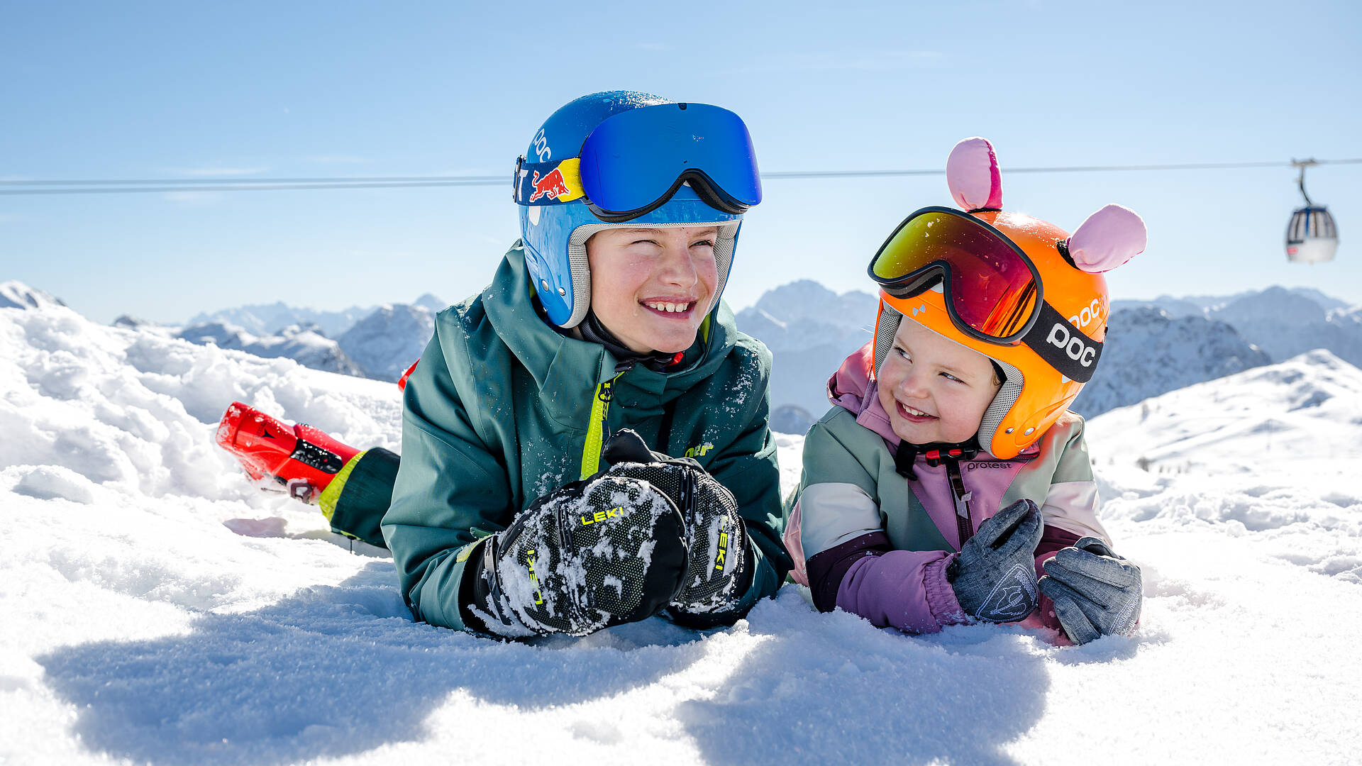 Zwei Kinder liegen im Schnee am Nassfeld.