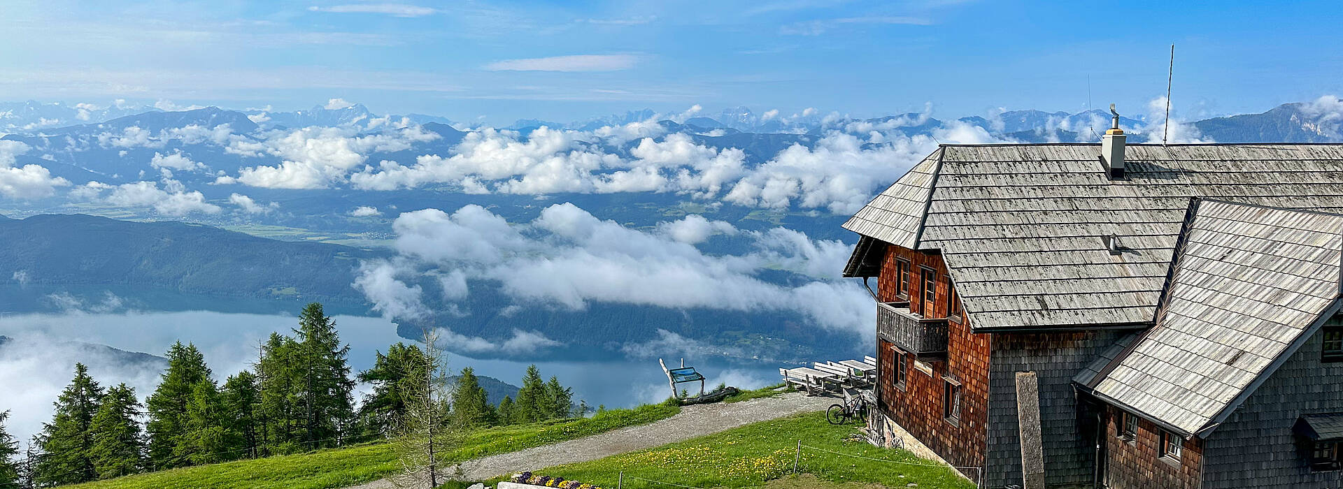 Die Alexanderhütte am Millstätter See ist von grünen Wiesen umgeben.