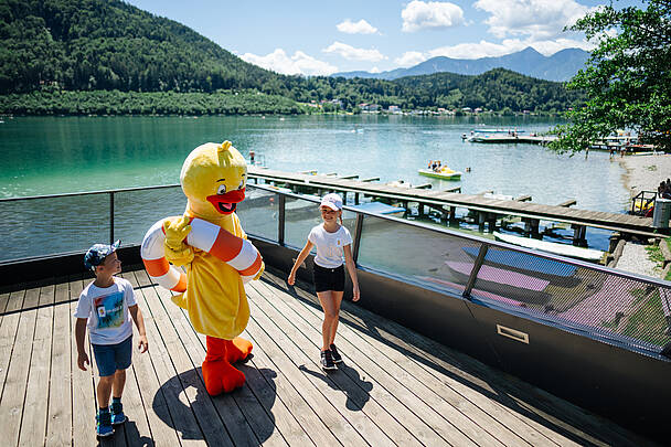 Zwei Kinder genießen das bunte Treiben beim Familien-Seefest am Klopeiner See in Suedkaernten.