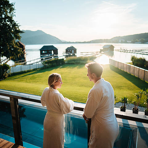 Paar steht am Balkon im Badehaus am Klopeiner See und genießt die Sonne